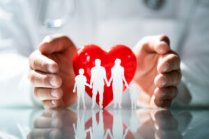 Concetto di protezione familiare: mani che circondano un cuore rosso e una famiglia stilizzata, simbolo di sicurezza, amore e tutela assicurativa nella vita quotidiana.