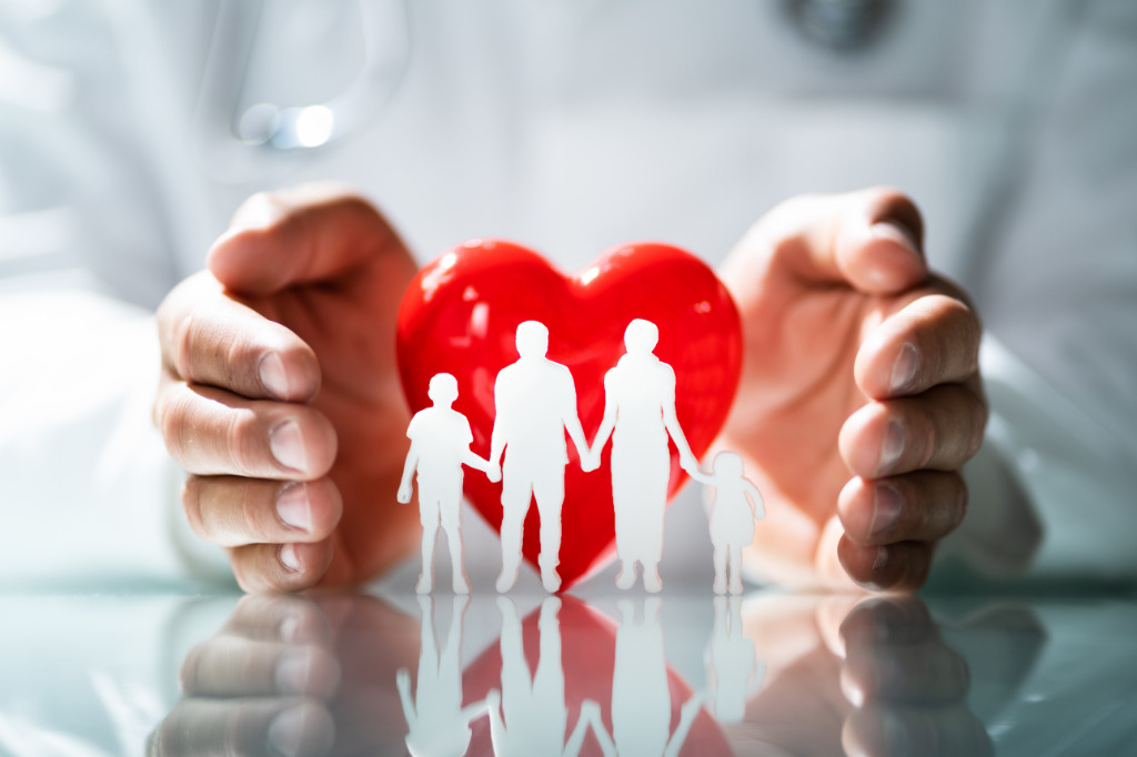 Concetto di protezione familiare: mani che circondano un cuore rosso e una famiglia stilizzata, simbolo di sicurezza, amore e tutela assicurativa nella vita quotidiana.